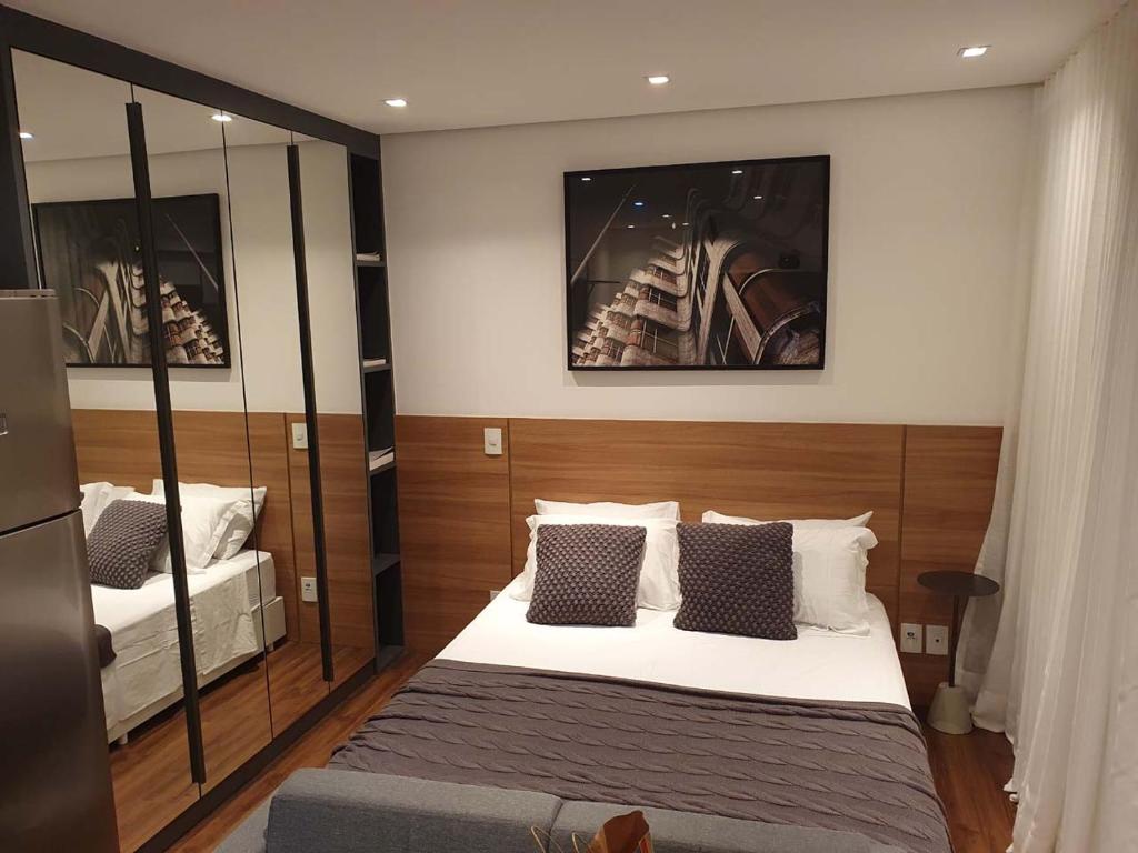 een slaapkamer met een bed en een spiegel bij Studio Aconchegante in Sao Paulo