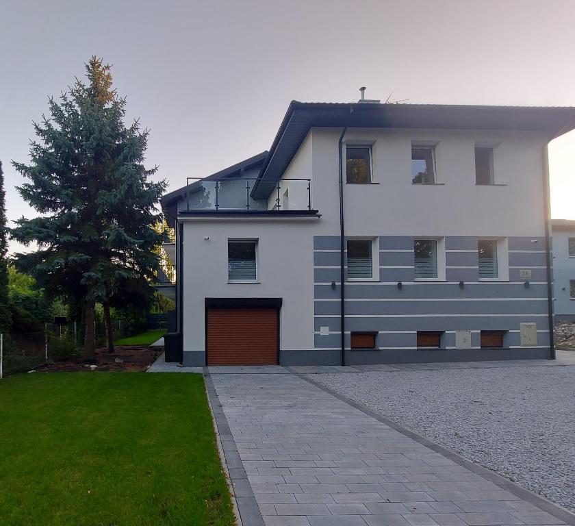 ein weißes Haus mit einer Garage und einem Baum in der Unterkunft Willa Vistula in Ciechocinek