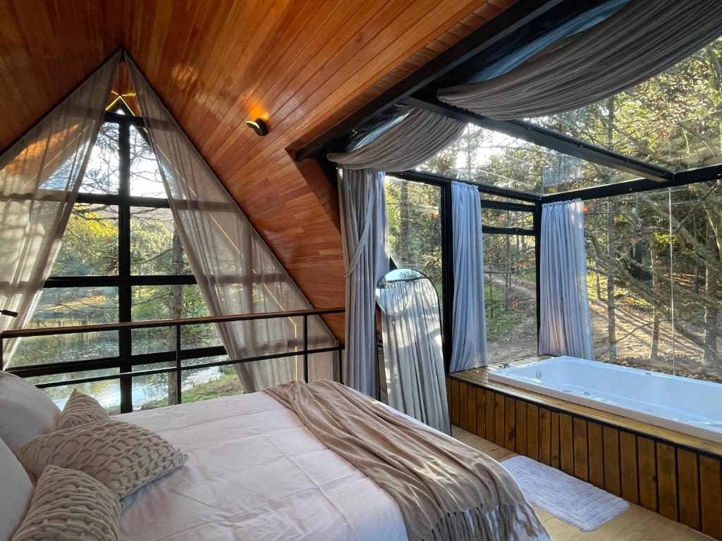 a bedroom with a bed and a tub in a room at Cabanas Jardim de Tereza in São Joaquim