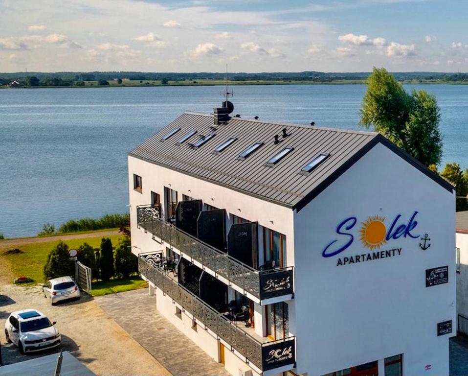 een gebouw met een zon op het dak naast het water bij SOLEK Apartamenty i pokoje gościnne in Mielno