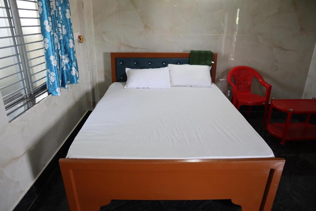 a bed in a room with two red chairs at Jagannatha Guest House in Puri