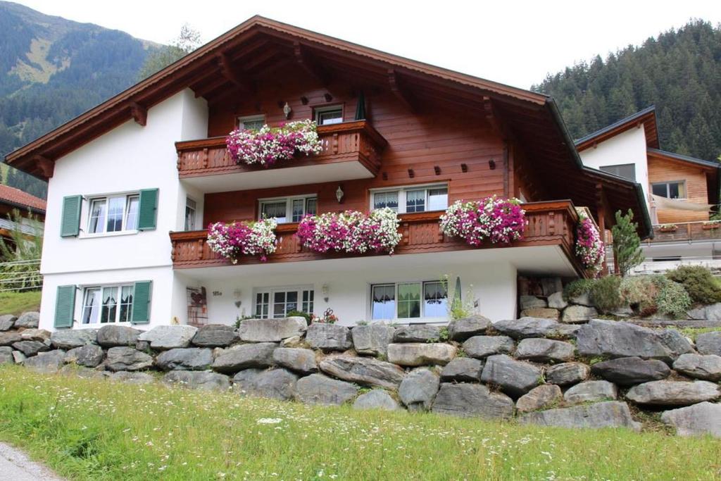 una casa con flores frente a una pared de piedra en Appartment Ganahl en Gaschurn