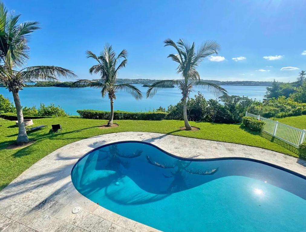 una piscina con vistas al agua y a las palmeras en Neston en Hamilton