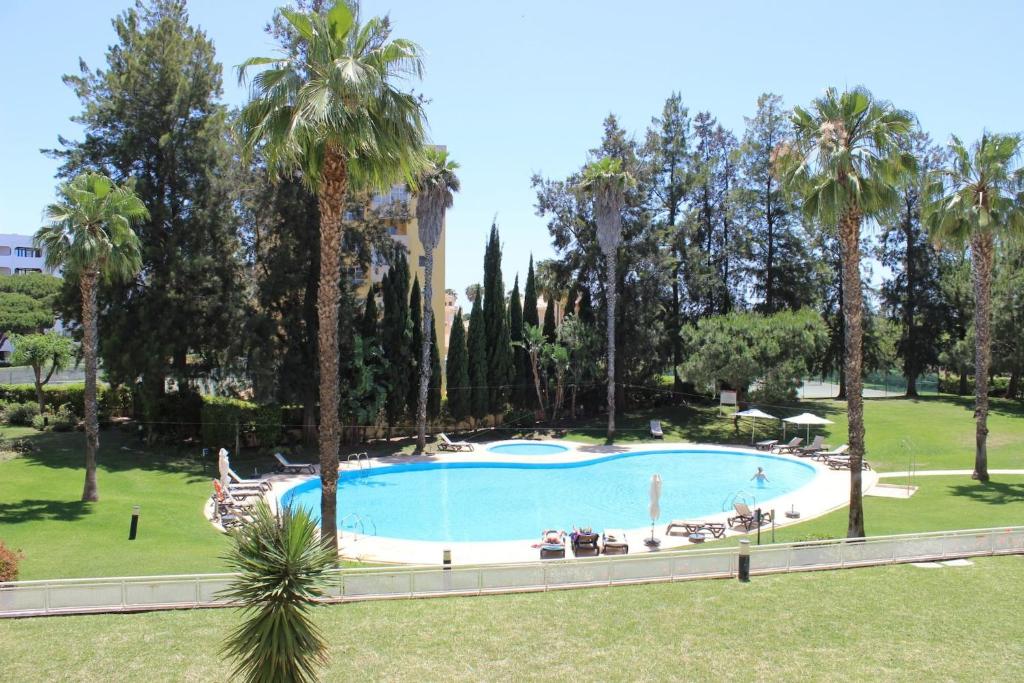 een groot zwembad in een park met palmbomen bij Da Praia Apartment - Pool & Tenis in Vilamoura