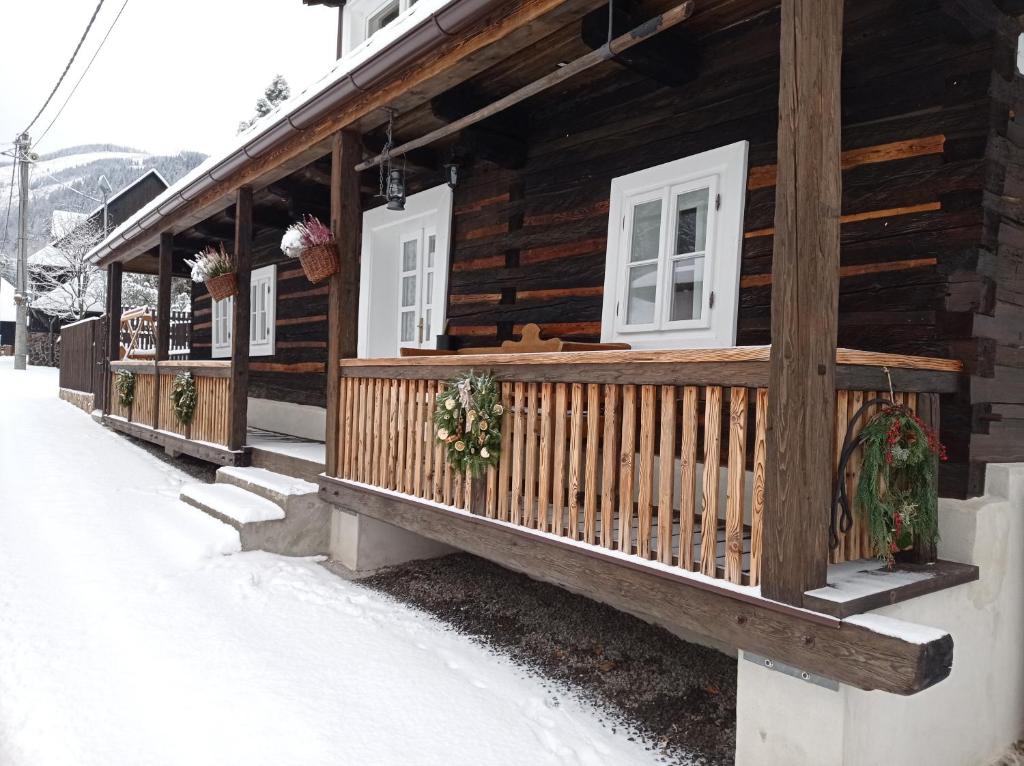 Cabaña de madera con ventanas blancas y nieve en Chalupa Bocza en Nižná Boca