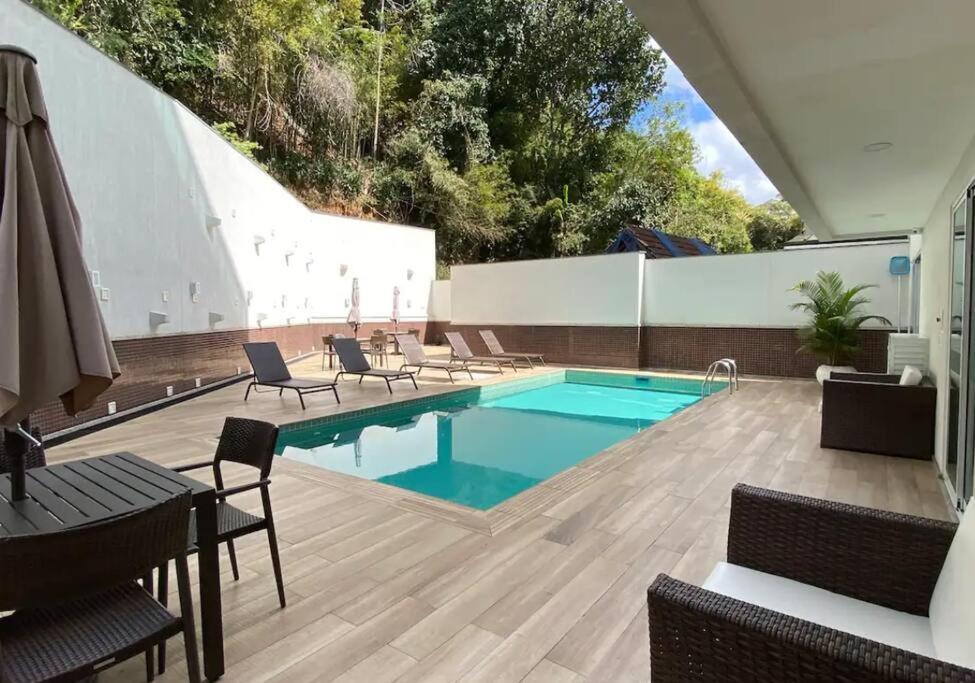 a swimming pool on a patio with chairs and a table at Loft 511 Super Aconchegante no Coração de Teresópolis in Teresópolis