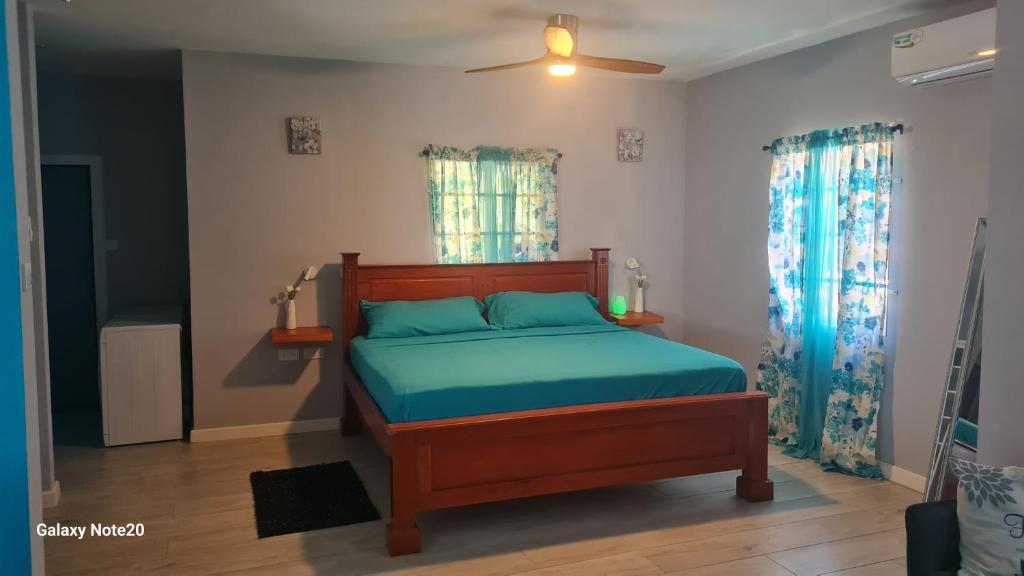 a bedroom with a bed with blue sheets and a fan at Coconut Creek Deluxe Suite in Hyde Park