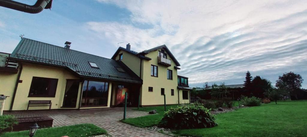 una gran casa amarilla con un patio verde en RelaxRitual en Līči