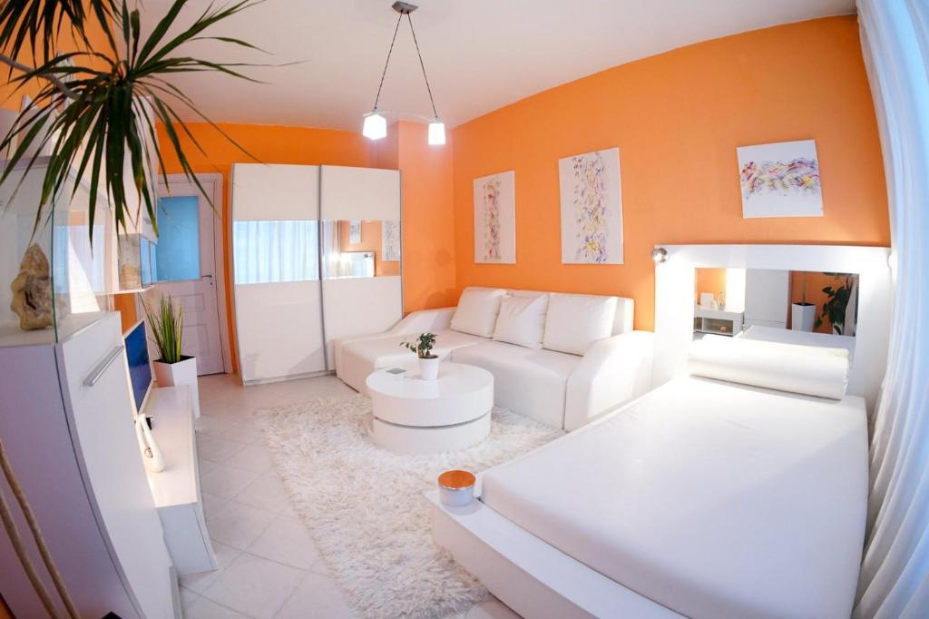 una sala de estar con muebles blancos y una pared de color naranja. en Alex Botique, en Varna