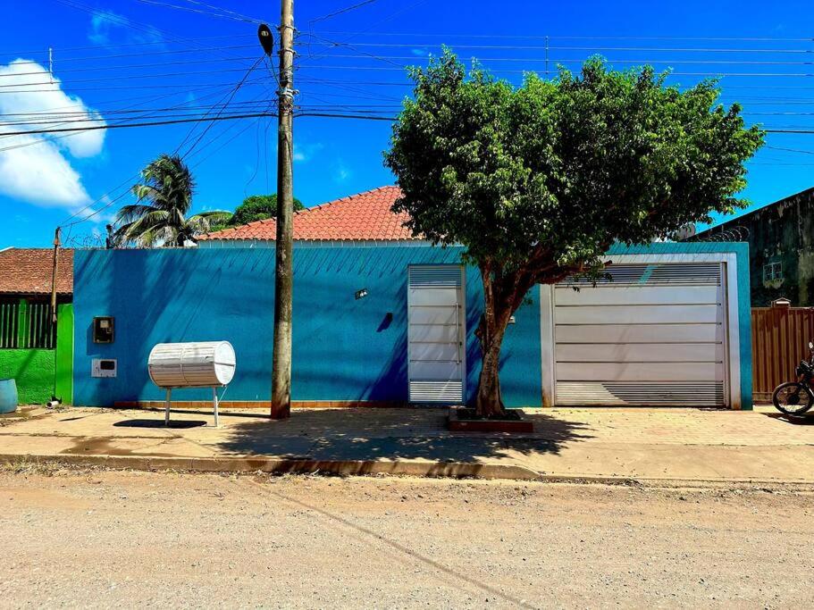 um edifício azul com uma árvore em frente em Blue Home em Bodoquena