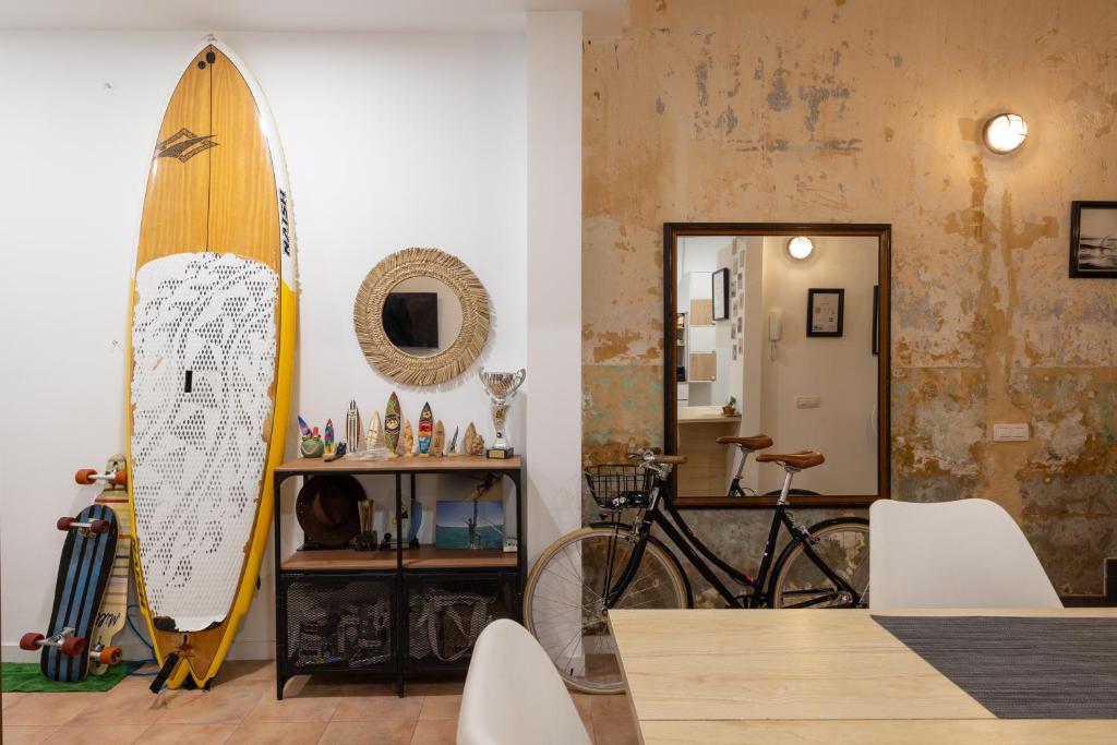 een surfplank die tegen een muur leunt naast een eetkamer bij Kite & Surf Nomad House in Las Palmas de Gran Canaria