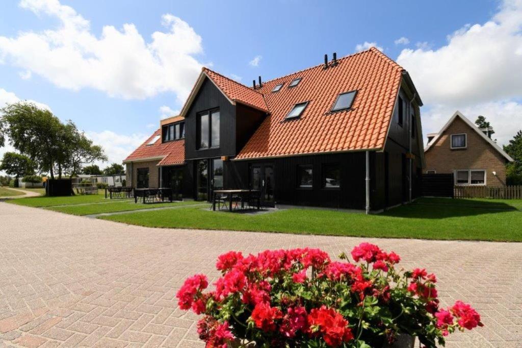 a black house with red flowers in front of it at Skylgerduin in Midsland