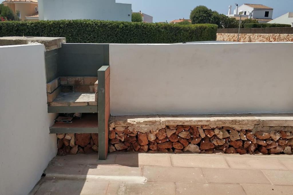 un muro di pietra con una panca accanto a un mucchio di tronchi di Apartamento con terraza y jacuzzi, zona ciutadella a Cala en Blanes