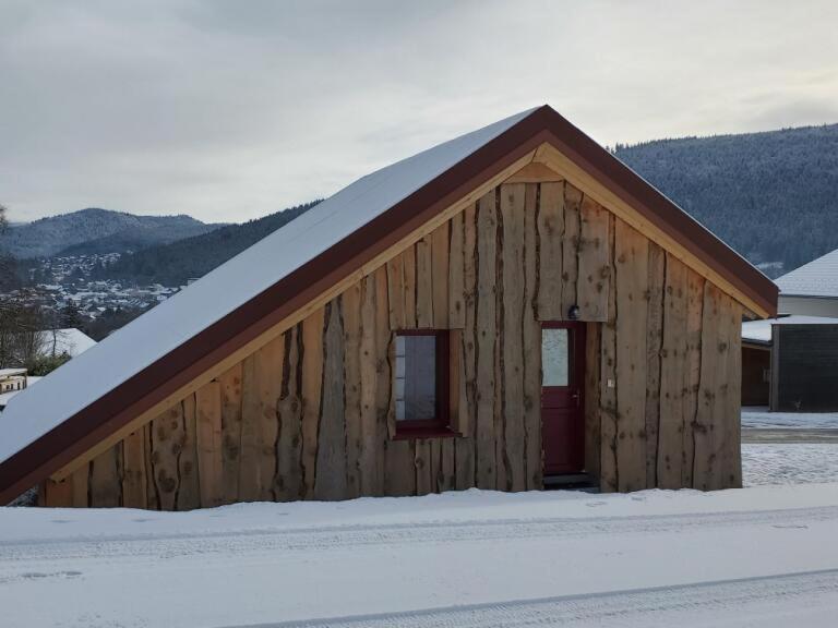 un edificio in legno con una porta rossa nella neve di Le chalet Lili a Gérardmer