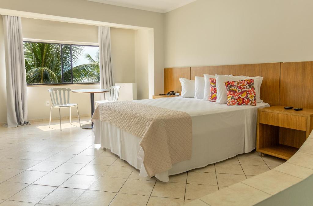 a bedroom with a bed and a table and a window at Ilha Porchat Hotel in São Vicente