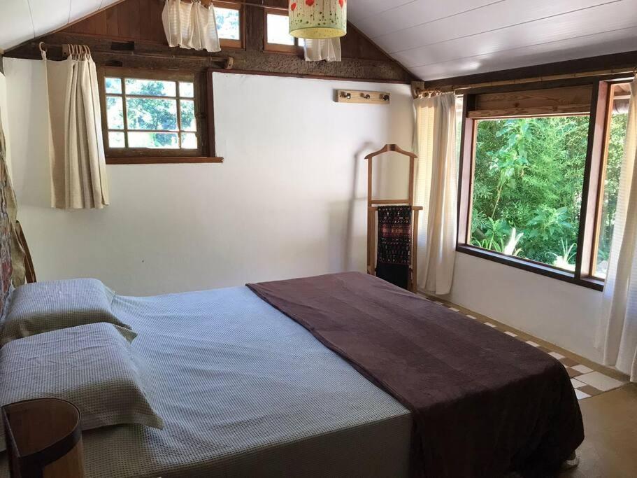 um quarto com uma cama num quarto com janelas em Chalé das Bromelias em Petrópolis