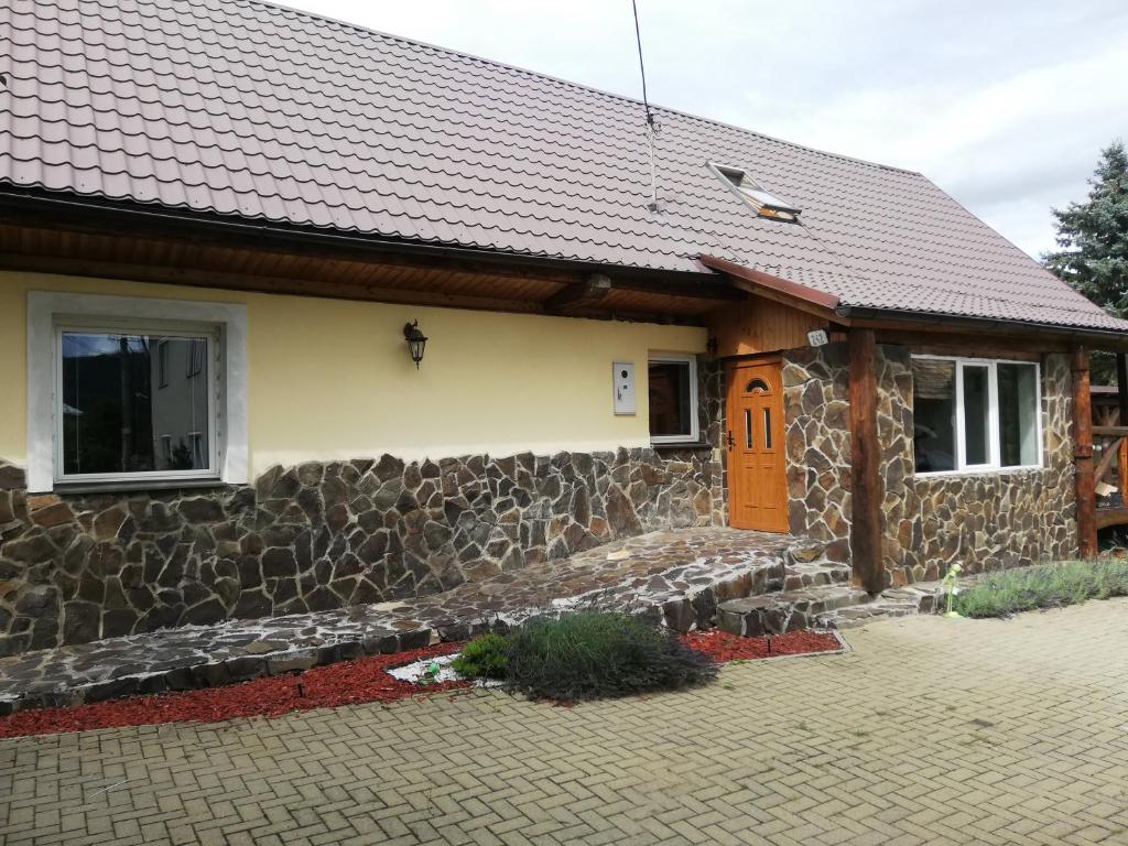 una casa con una pared de piedra y una puerta marrón en Chata Pod Lipou en Bacúch