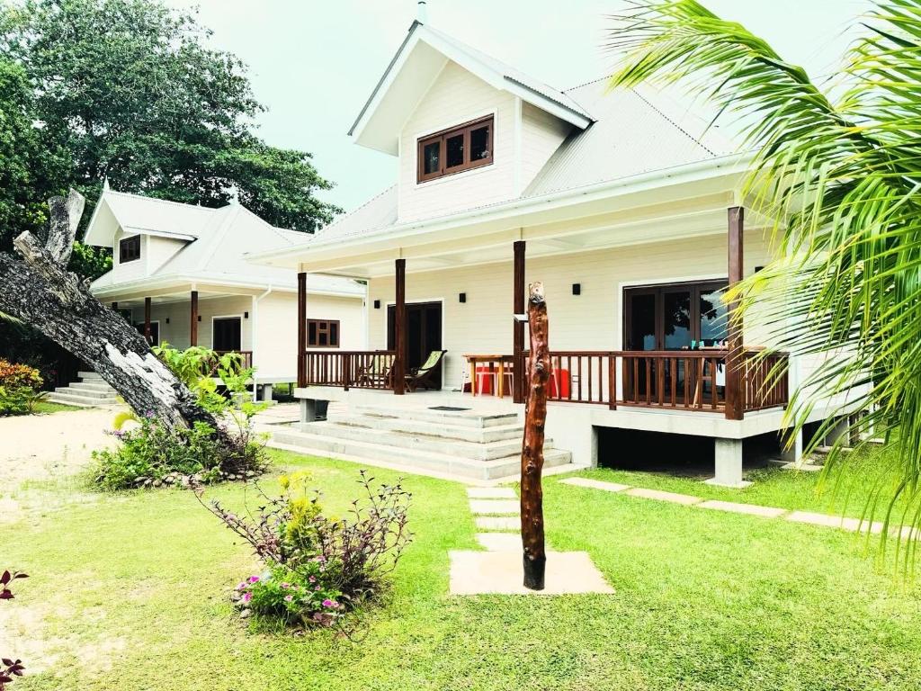 uma casa branca com um alpendre e um quintal em Digwa Beach Chalet em La Digue