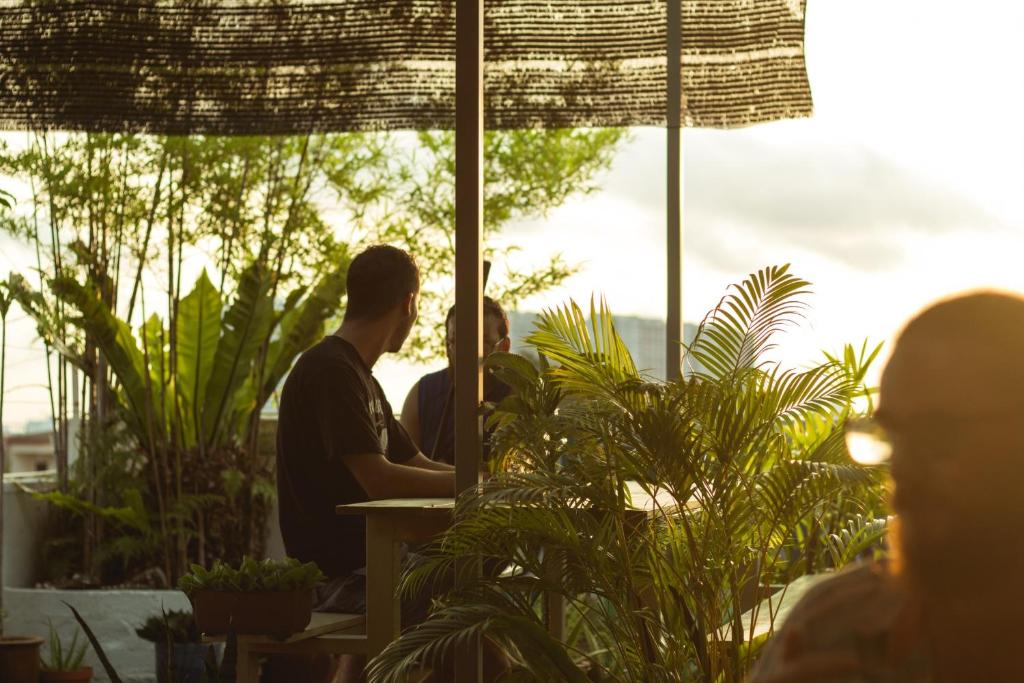 dois homens sentados numa mesa numa sala com plantas em Ringo's Foyer em Malaca