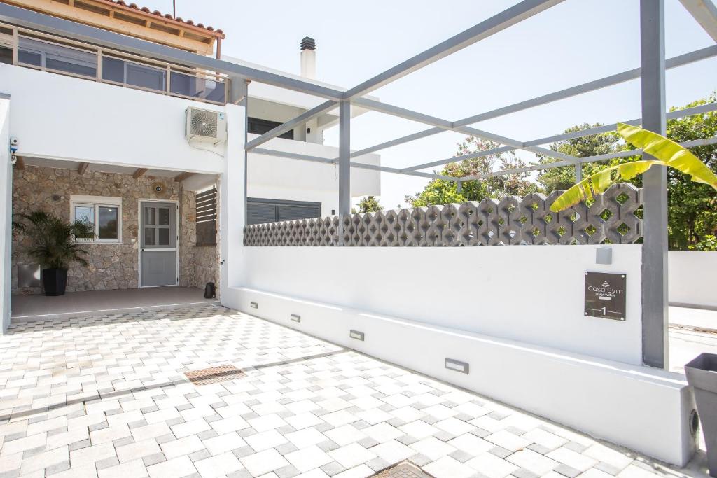 an outdoor patio with a white wall and a tile floor at Casa Sym Faliraki in Faliraki