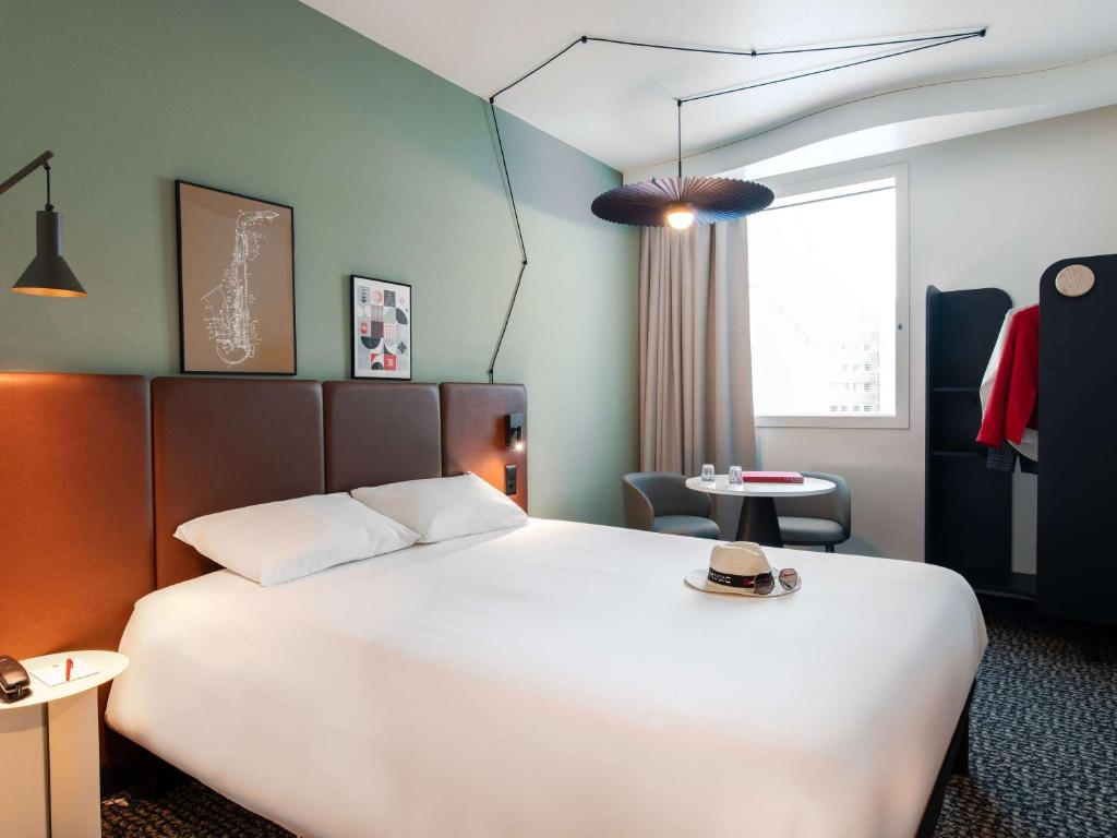 Cette chambre dispose d'un grand lit avec un chapeau. dans l'établissement ibis Lausanne Centre, à Lausanne