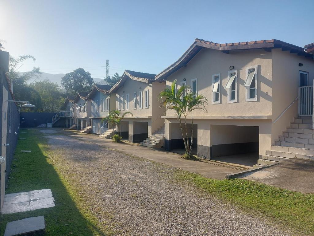 uma fila de casas numa estrada de terra em Casas em Condomínio próximo da praia com 2 dormitórios, churrasqueira e 3 vagas de garagem em Ubatuba