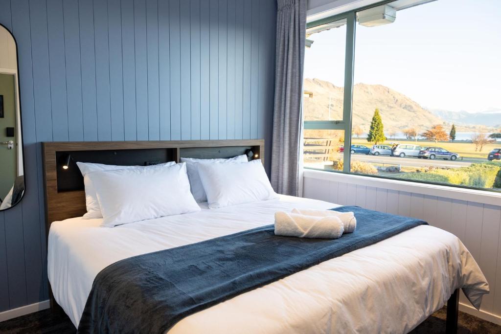 een slaapkamer met een groot bed en een groot raam bij Haka House Wanaka in Wanaka