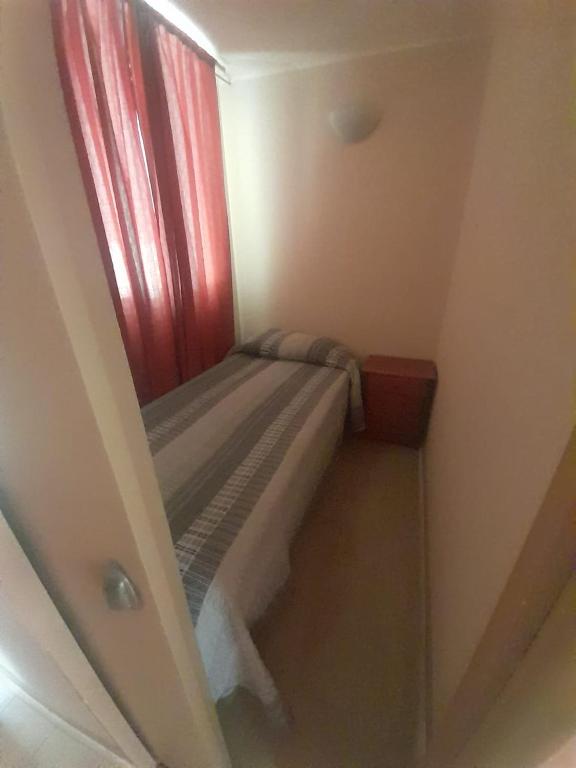 uma pequena cama num pequeno quarto com uma janela em Retamilla 409 em Huasco