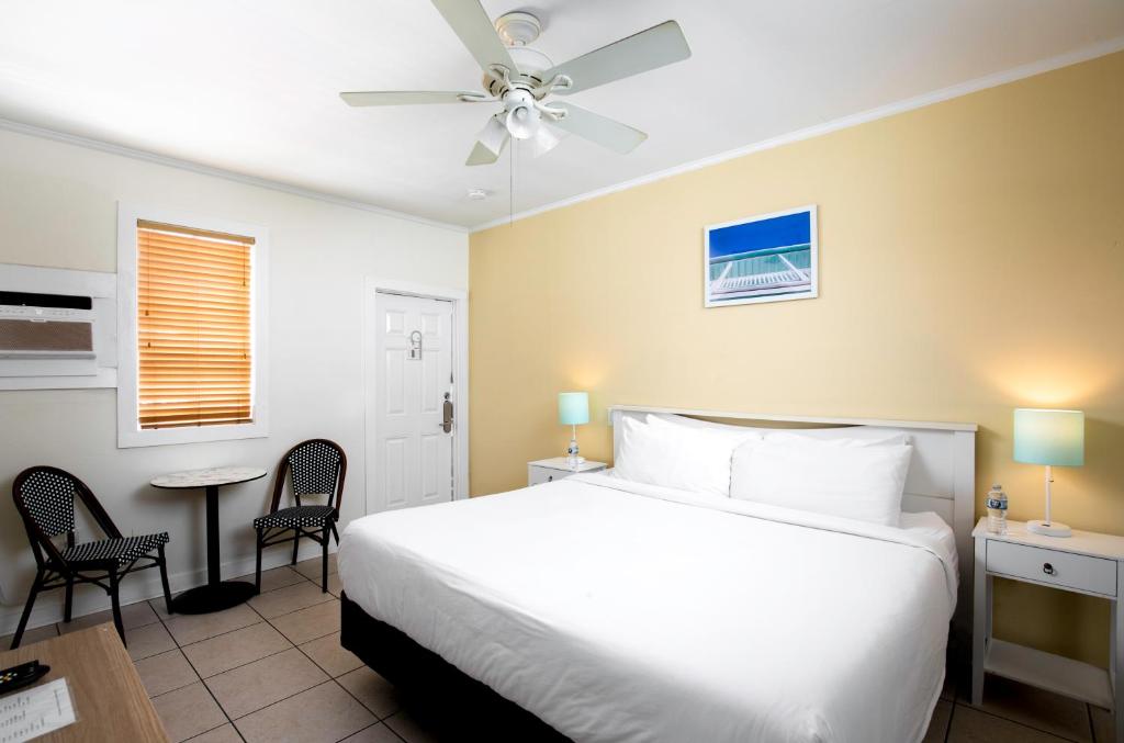 1 dormitorio con 1 cama blanca, mesa y sillas en Southernmost Inn Adult Exclusive en Cayo Hueso