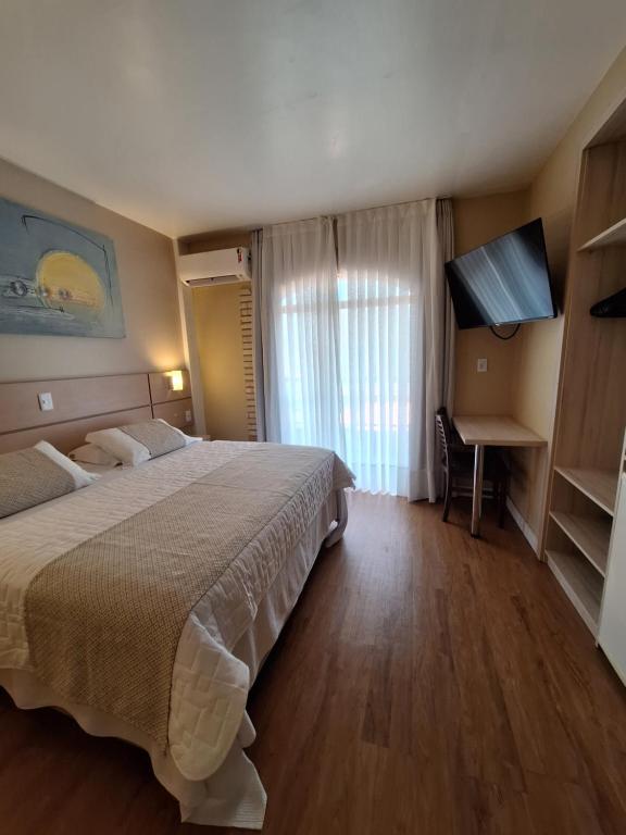 Habitación de hotel con cama y TV de pantalla plana. en Hotel Joao de Barro en Itajaí