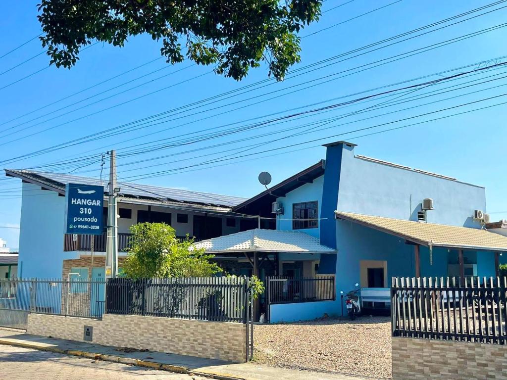 un edificio azul con un cartel delante en Hangar Pousada en Navegantes