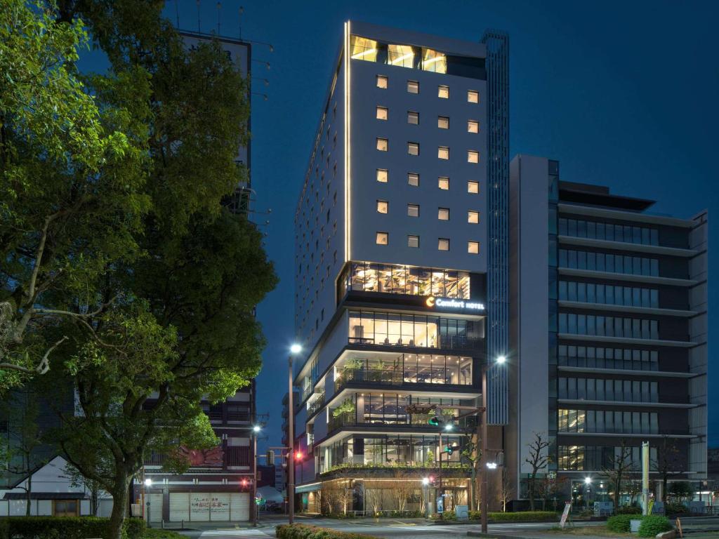 un edificio alto con luces encendidas en una ciudad por la noche en Comfort Hotel Yokkaichi en Yokkaichi