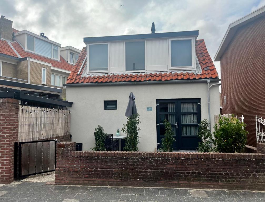 Casa blanca con mesa y sombrilla en T-Rots, prachtig zomerhuis en Noordwijk aan Zee