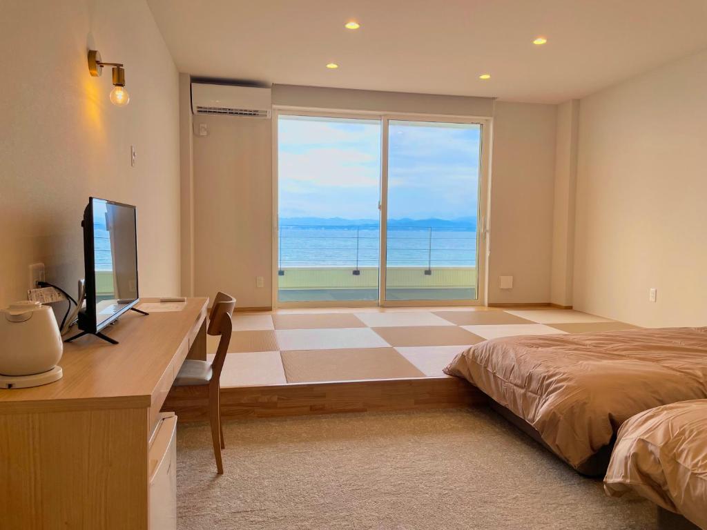 1 dormitorio con 1 cama y escritorio con TV en QUAYTH l キース en Shirahama