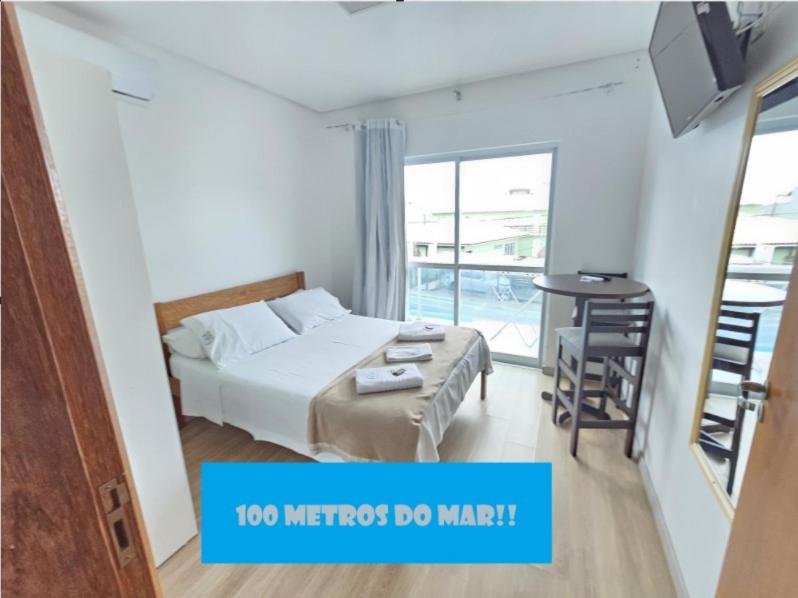 1 dormitorio con cama, escritorio y ventana en Barra da Lagoa Guest House, en Florianópolis