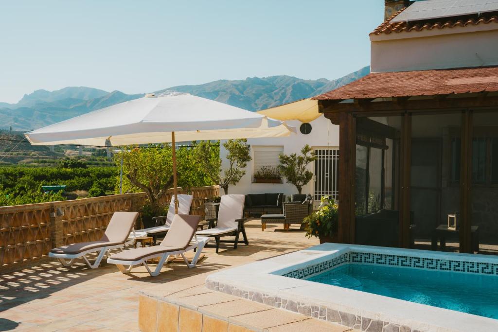 un patio con sillas y una sombrilla junto a la piscina en Casa Julia Costa Tropical en Salobreña