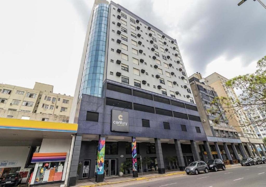 un gran edificio en una calle de la ciudad con coches aparcados delante en Coliving Century Park by My Way en Porto Alegre