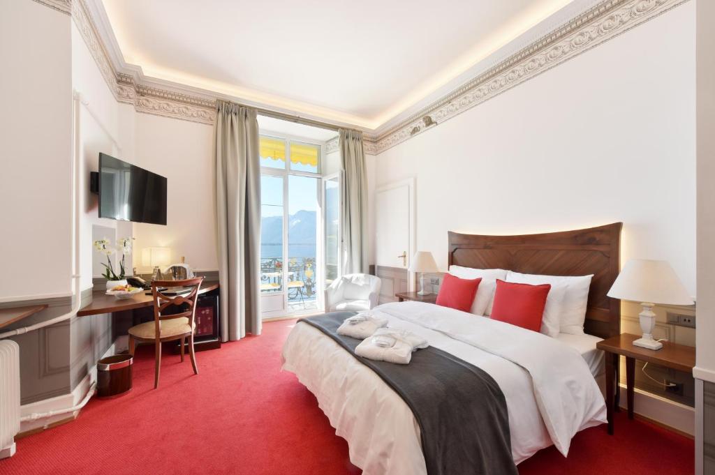 a bedroom with a large bed with a red carpet at Golf Hotel René Capt in Montreux