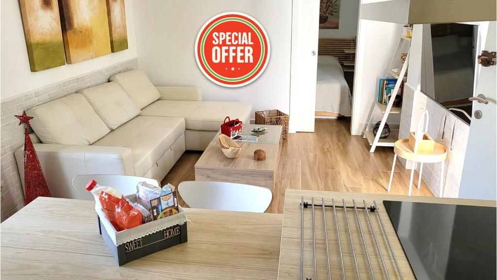 een woonkamer met een bank en een bord met speciale aanbieding bij Apartamento EL REAL - Espartinas - SEVILLA in Espartinas