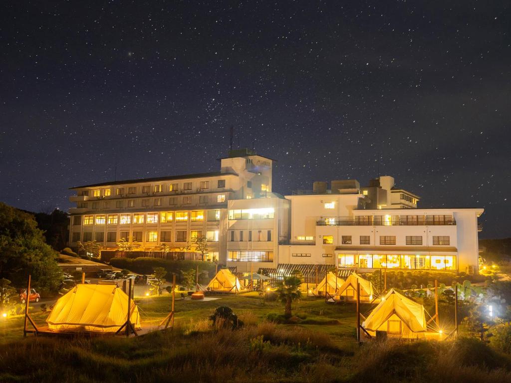 een groot gebouw met tenten er 's nachts voor bij Ooedo Onsen Monogatari Shima Saichoraku in Shima