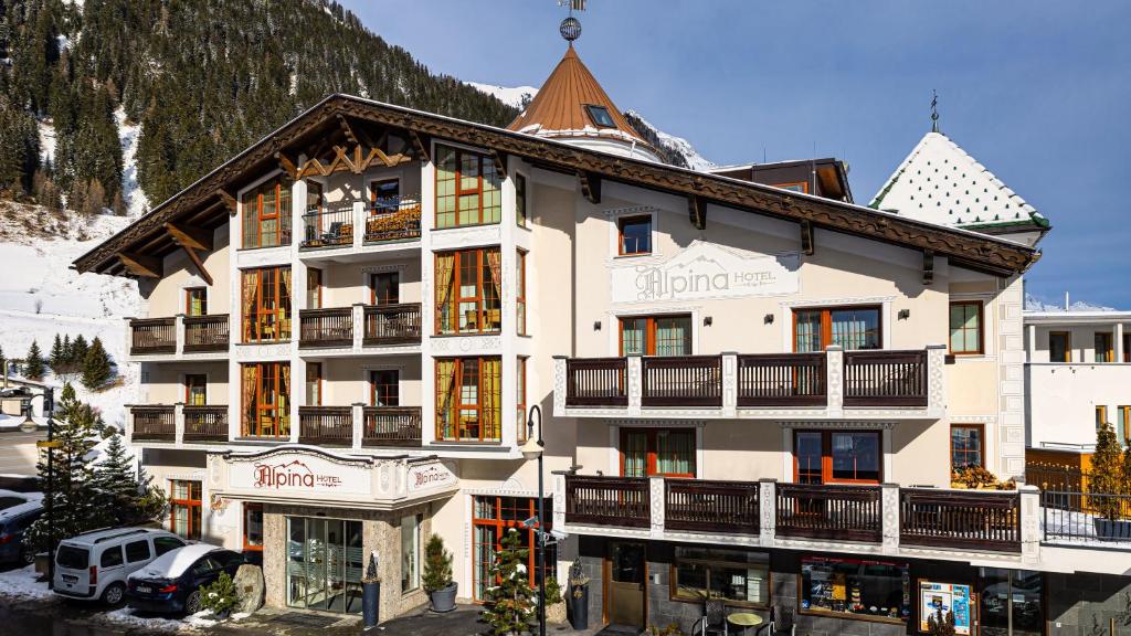 un gran edificio blanco con una montaña cubierta de nieve en Hotel Alpina, en Ischgl