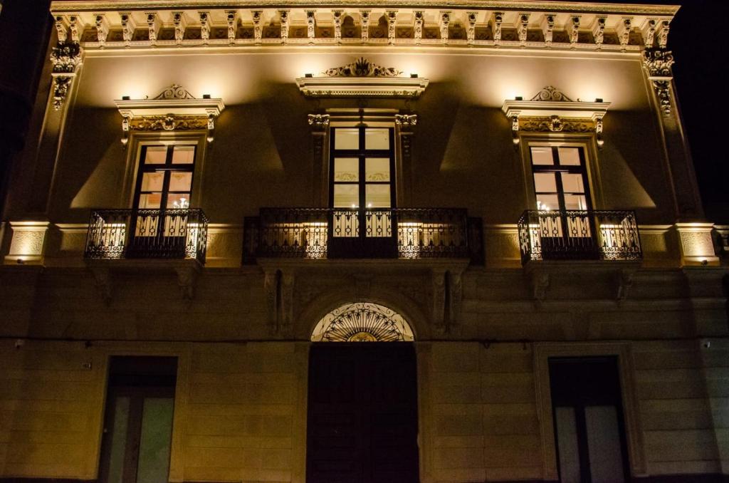 a building with windows and a balcony at night at Palazzo Fiammingo Rooms in Belpasso