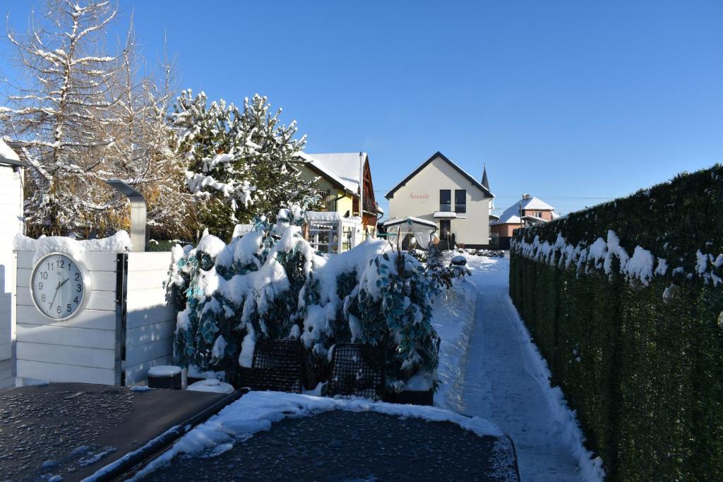 um quintal coberto de neve com um relógio sobre uma cerca em Serenity em Pribylina