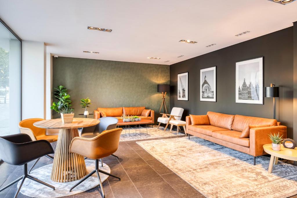 uma sala de estar com sofás e mesas laranja em Park Inn by Radisson Antwerp City Centre em Antuérpia