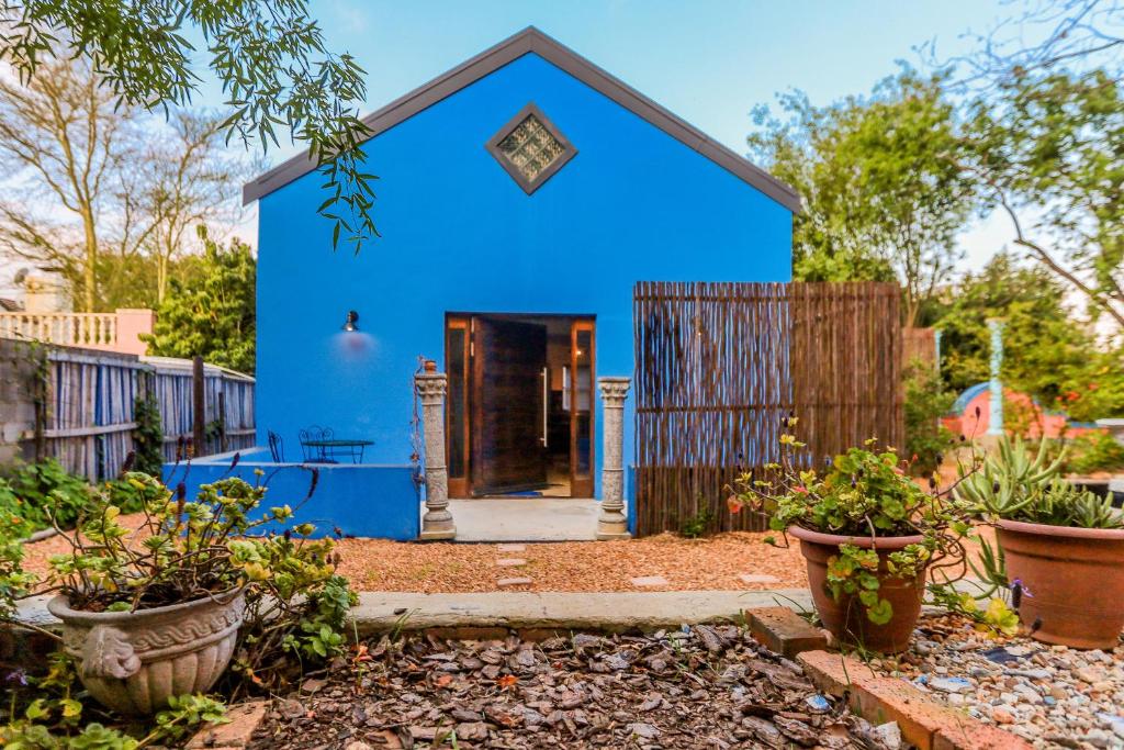 a blue house in a yard with potted plants at Bamboo Cottage in Riebeek-Kasteel