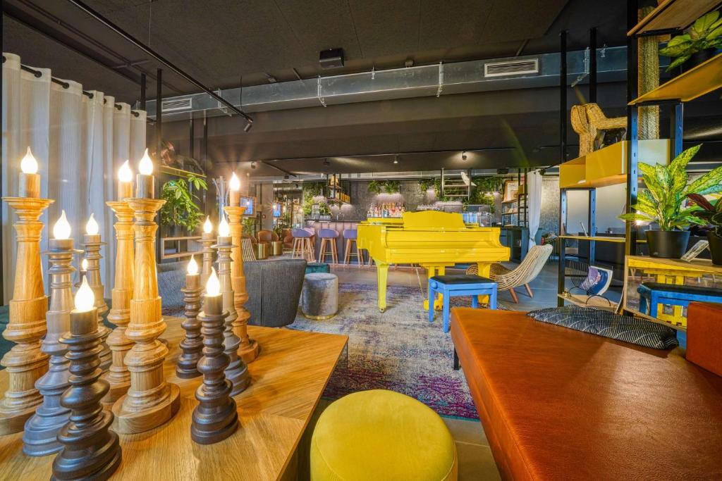 a restaurant with tables and chairs and a yellow piano at NinetyNine Hotel Augsburg, Trademark Collection by Wyndham in Augsburg