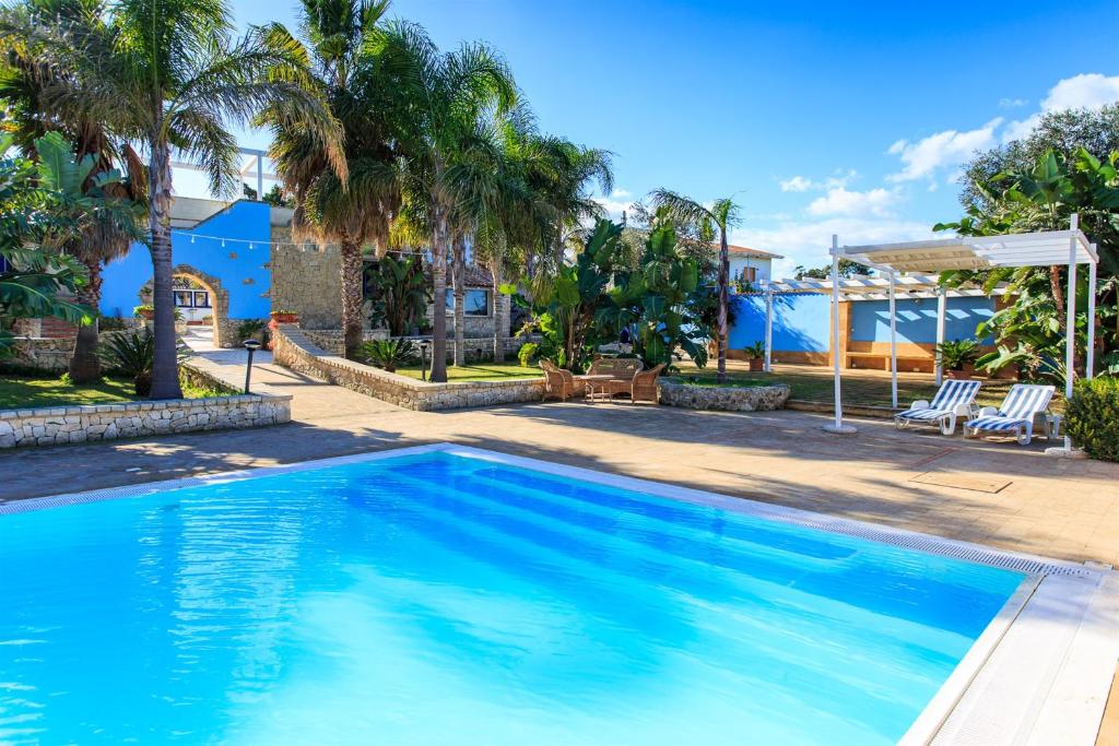 einen Pool in einem Garten mit Palmen in der Unterkunft Borgo Marino Plemmirio in Syrakus