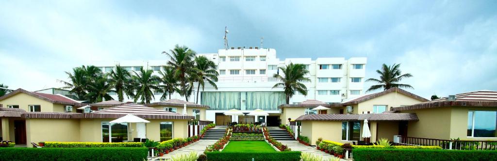 un gran edificio blanco con palmeras delante en Hotel Holiday Resort, en Puri