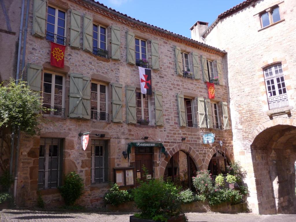 um grande edifício de tijolos com bandeiras em Chambres d'hôtes l'Escuelle des Chevaliers em Cordes-sur-Ciel