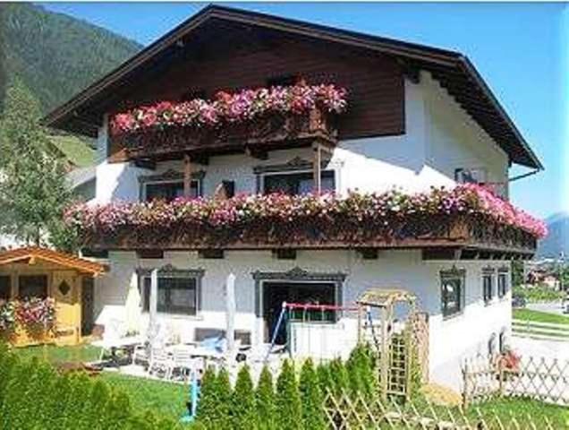 Una casa blanca con flores encima. en Pension Kristall en Neustift im Stubaital